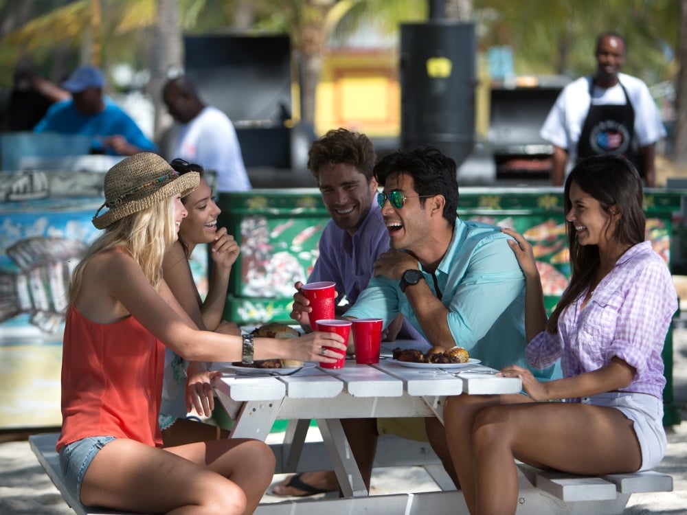 A group of young friends laugh at a picnic table in Nassau Bahamas. 