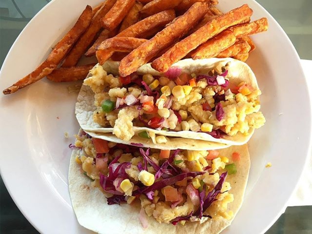 Shrimp tacos with sweet potato fries on a white plate.