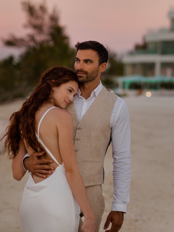 couple in wedding attire embracing on the beach