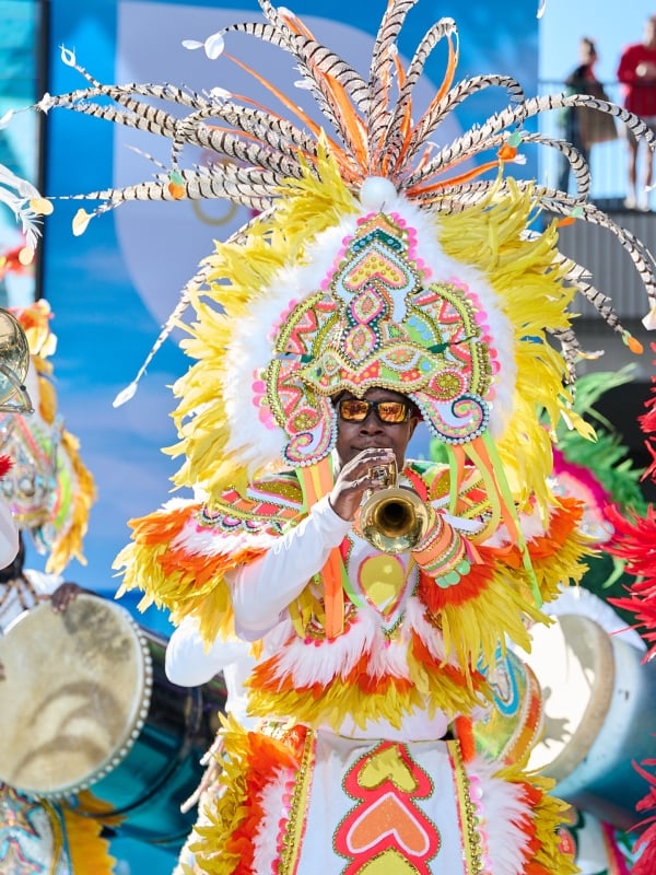 Bahamian musicians play instruments in elaborate costumes.