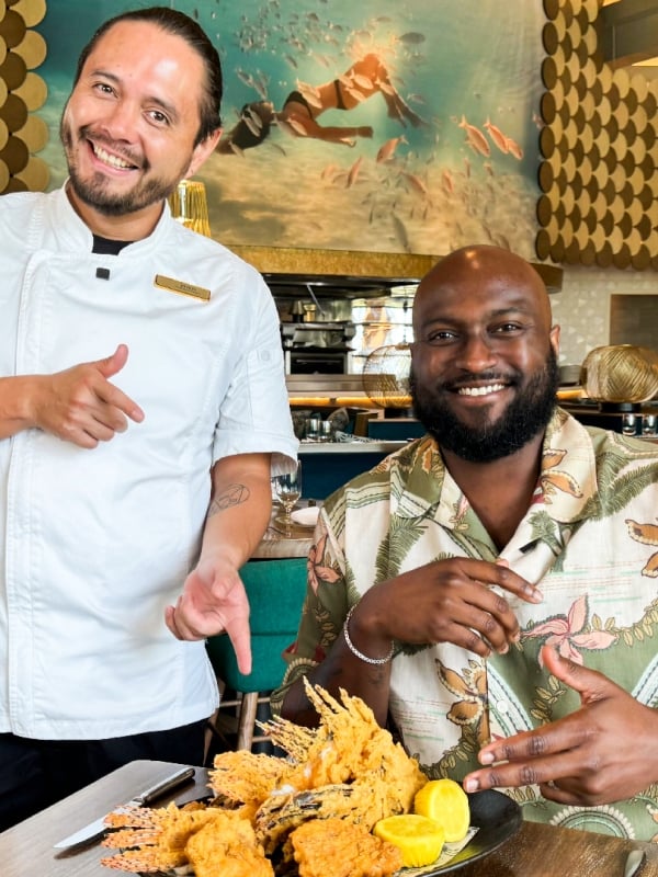 two men posing with food at a restaurant