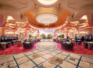 Luxury interior of Baha Mar casino with large chandelier, card tables, and slot machines.