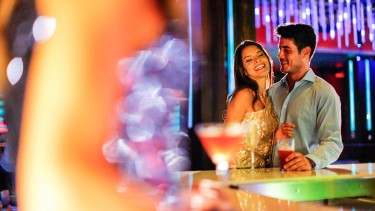 A man and a woman standing together romantically at a bar.