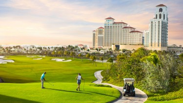 A man and a woman playing golf at Baha Mar Royal Blue Golf course.