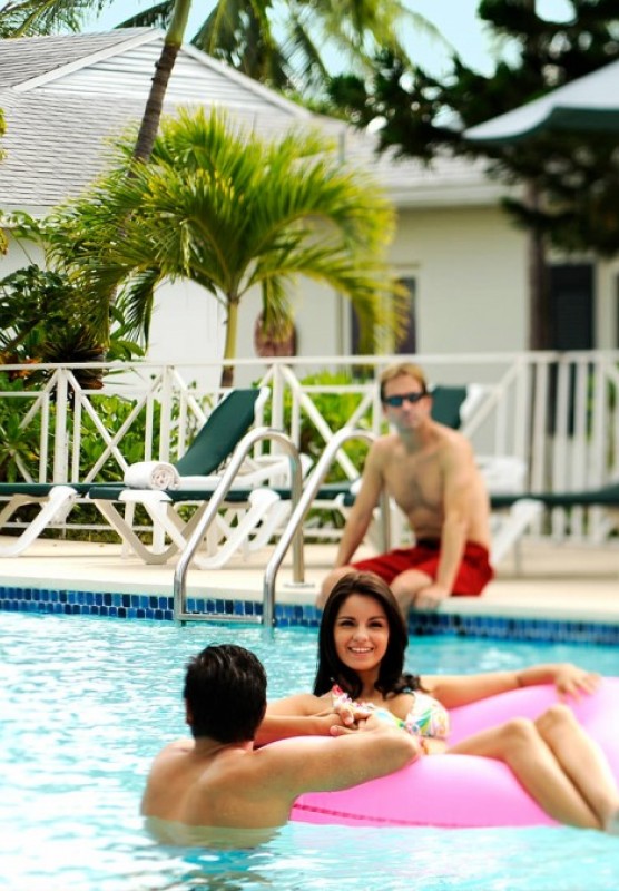 Groups of young people relax in and around a resort pool.