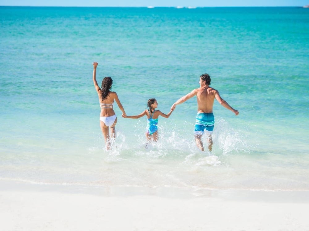 A family running into the water in Nassau