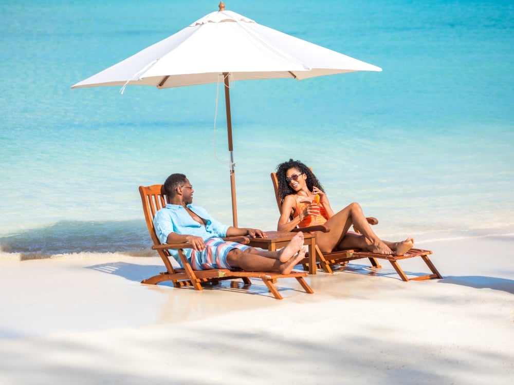 A couple sitting on the beach in Nassau Paradise Island in deck chairs