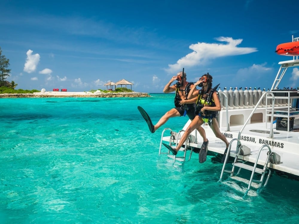 A couple jumping into the water to snorkel from a boat