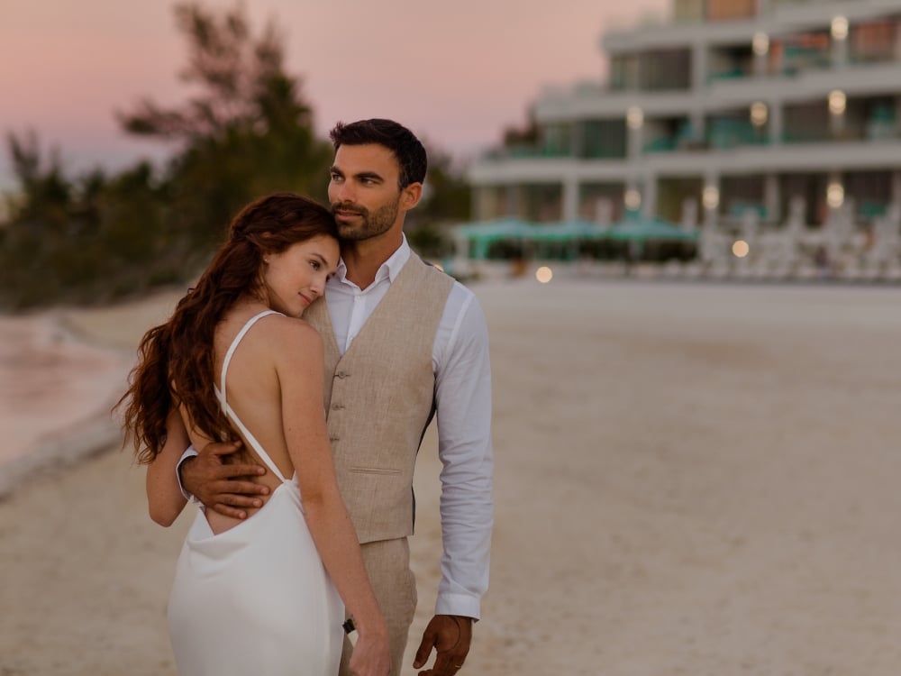 couple in wedding attire embracing on the beach