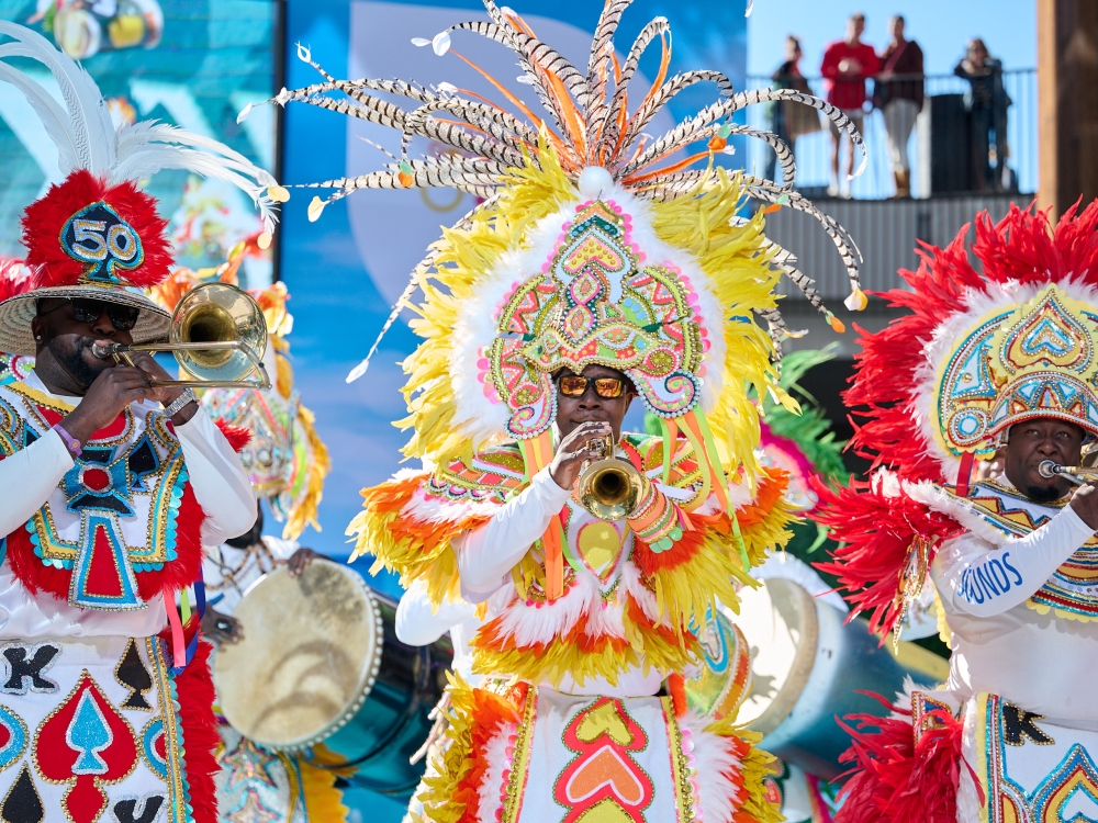 Bahamian musicians play instruments in elaborate costumes.