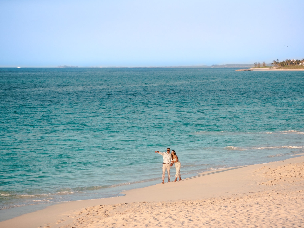 A couple walks along the beach in The Bahamas