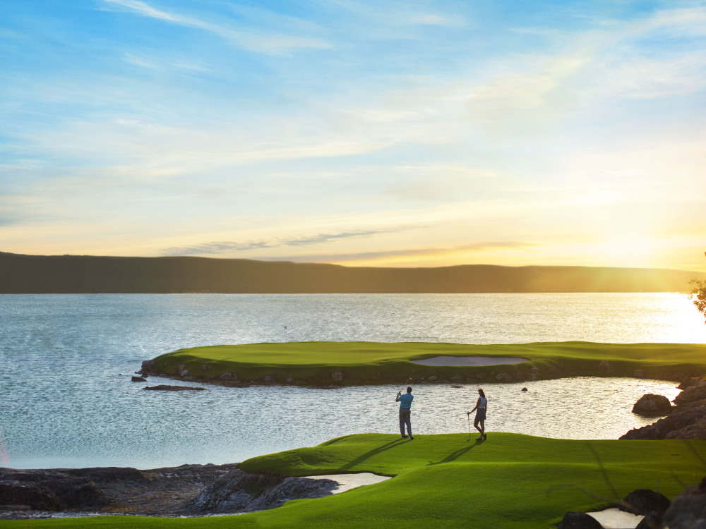 People playing golf at sunset