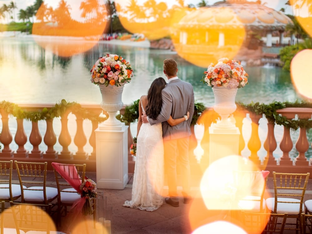 A couple stands on a balcony in their wedding attire.