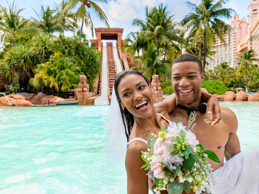 A couple in wedding attire in front of a waterslide.