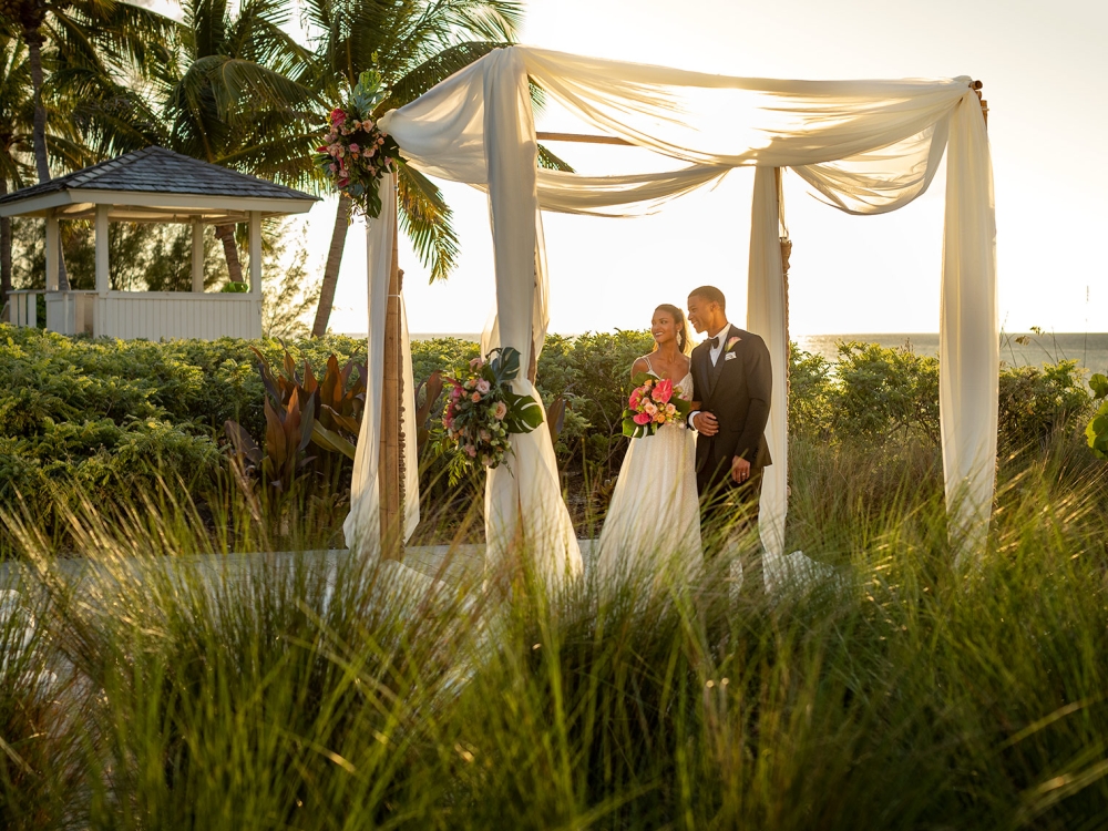 Couple getting married under canopy outside in the grass