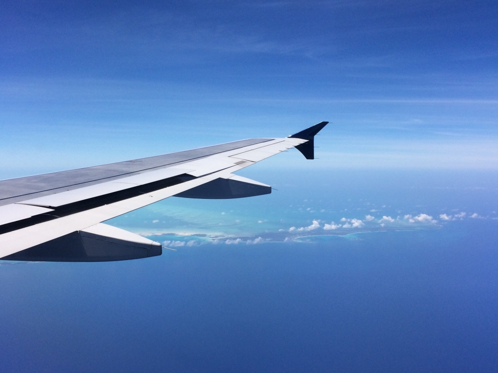 An airplane wing with the Bahamas islands in the background. 