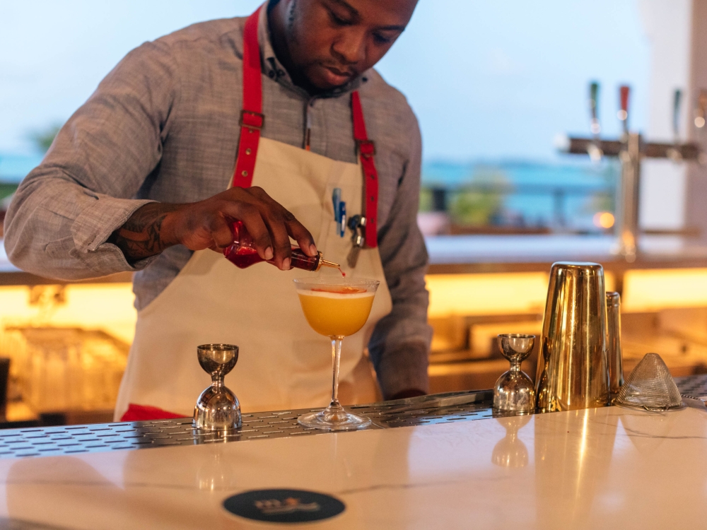 A bartender tops a cocktail with bitters.