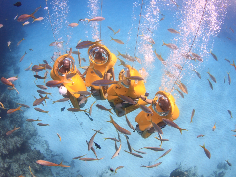 Four vacationers enjoy the Stuart Cove's SUB Bahamas experience surrounded by fish in the crystal-clear waters of The Bahamas.