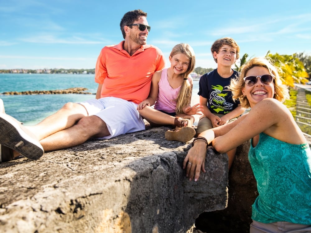 A family of four lounges in the sun at a historic fort in The Bahamas.