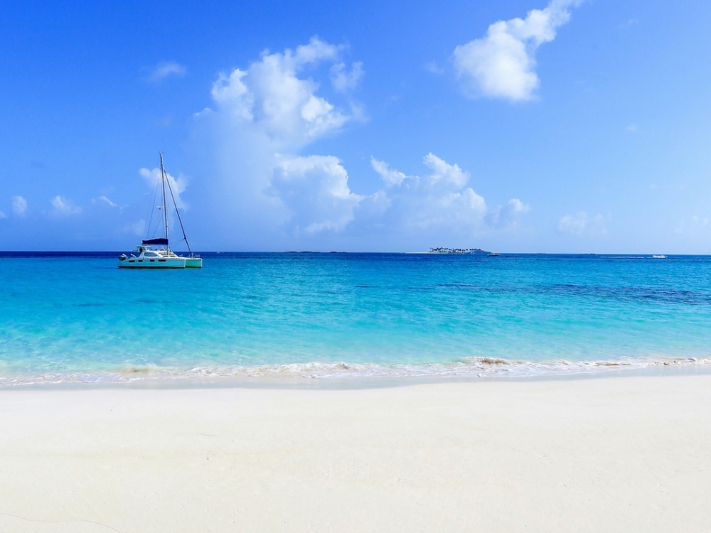 A boat anchored off the shore of a beautiful Bahamas beach.