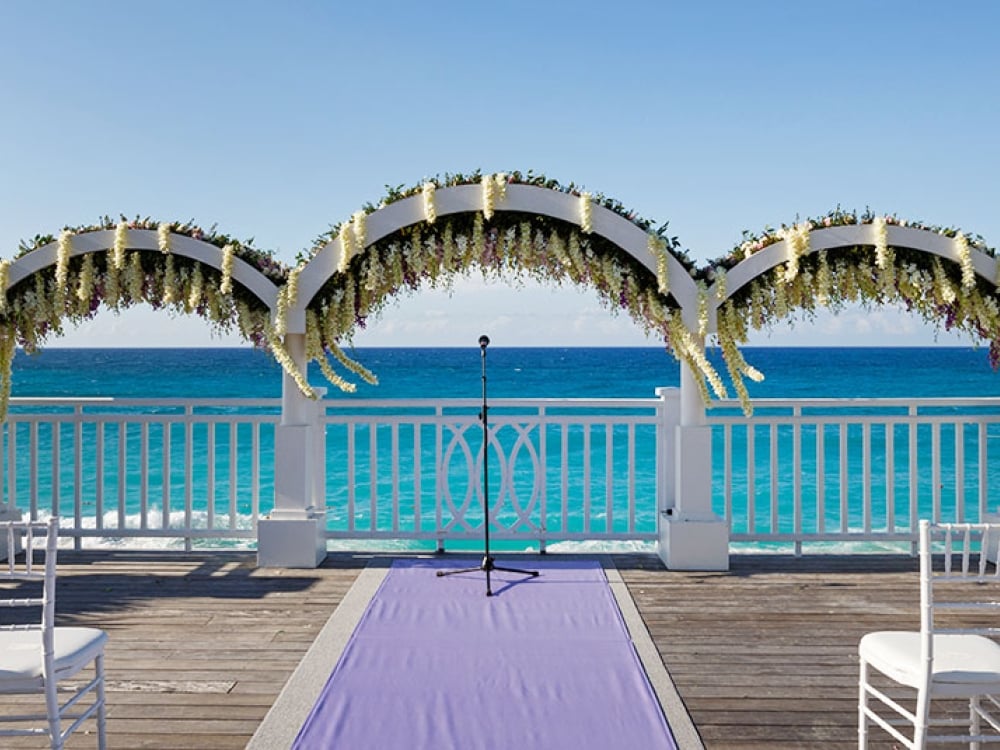 Wedding arches overlook the turquoise blue waters of the Bahamas at a destination wedding ceremony. 
