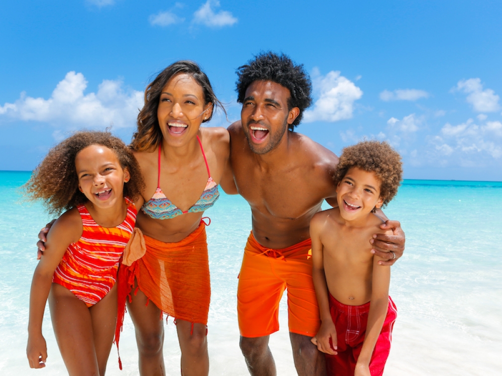 A family of four poses for a photo on the beach in Nassau Paradise Island. 