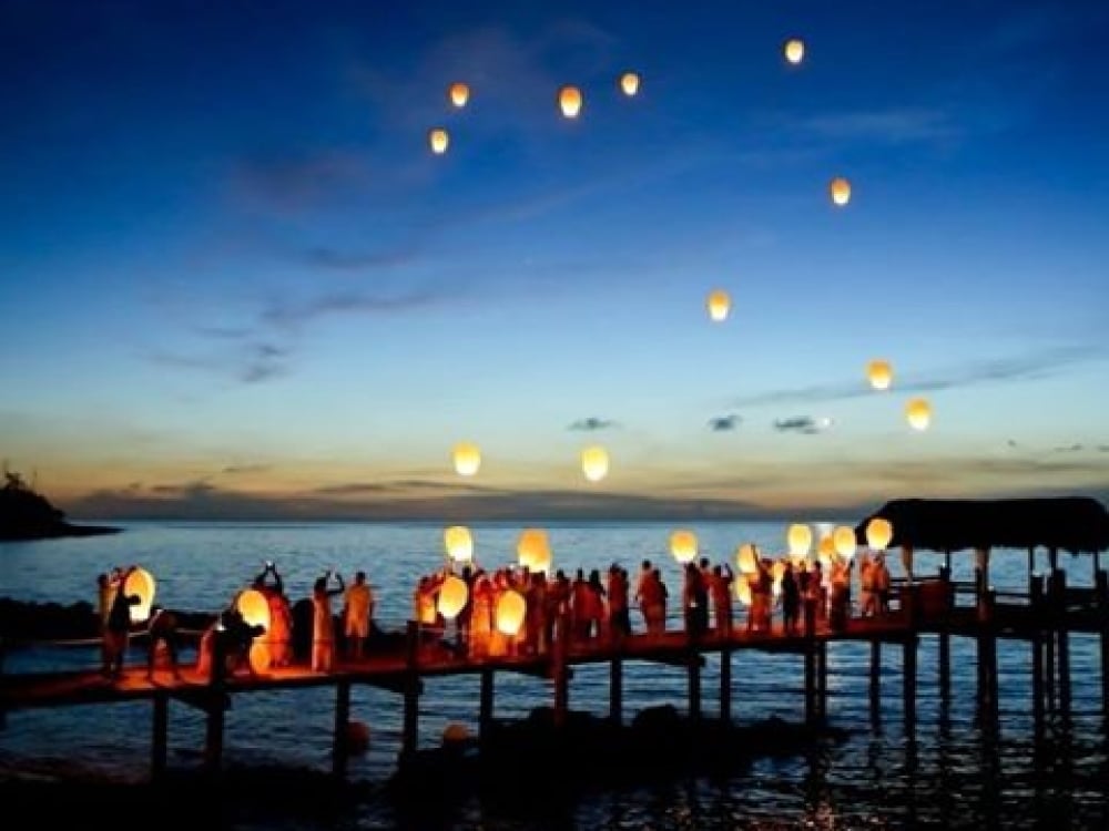 Wedding guests let lanterns float into the clear evening sky at a Bahamas destination wedding.