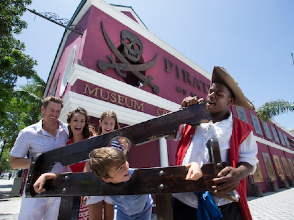 A family and a historical interpreter have fun outside the Pirate of Nassau Museum