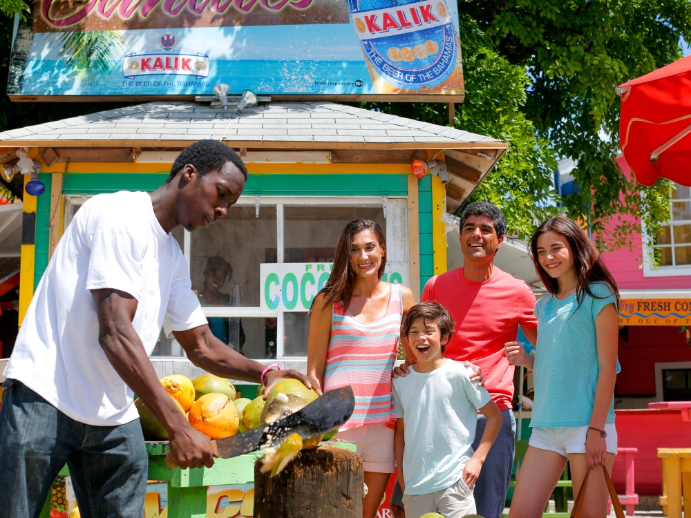 A man cutting a coconut for a family.