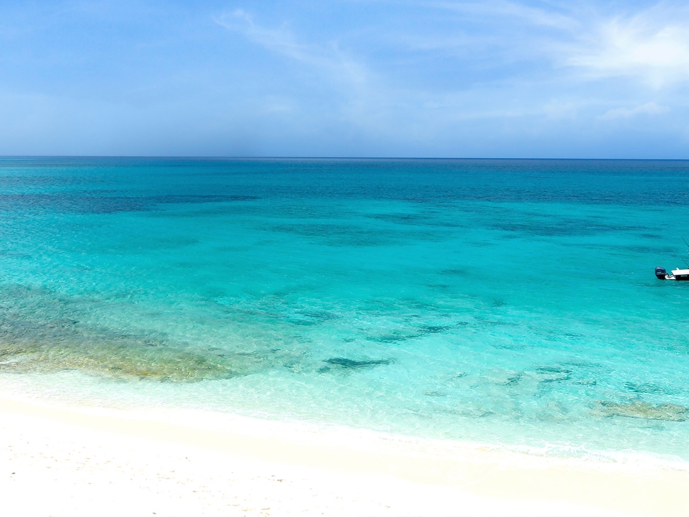 A small motor boat sailing through clear turquoise waters on a beautiful day.