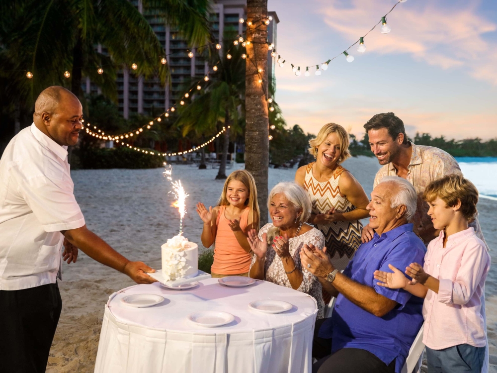 A family celebrates with cake on the beach at Atlantis, Paradise Island.