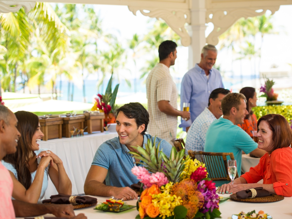 A group of friends enjoys a Bahamian-themed party at a tropically decorated table.