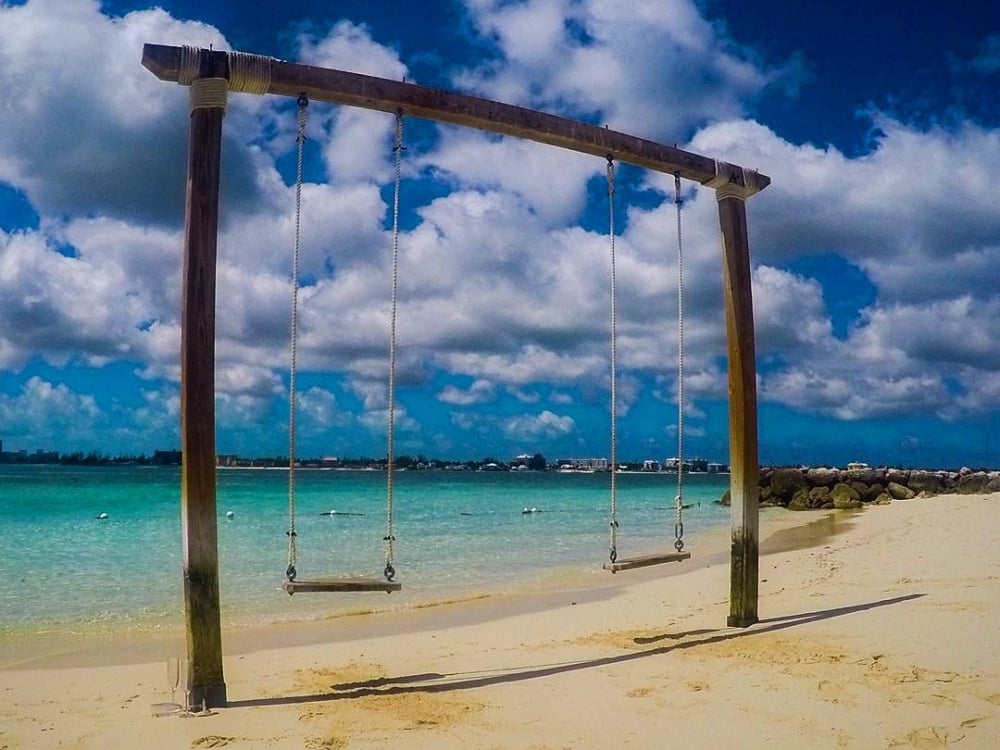 A rustic swingset for two on a beach at Sandals Royal Bahamian all-inclusive resort.