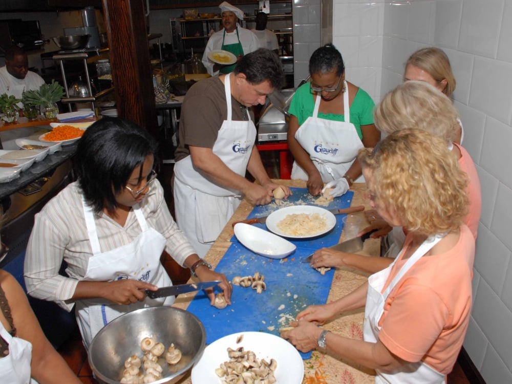 A group of people in aprons prepare food around a table