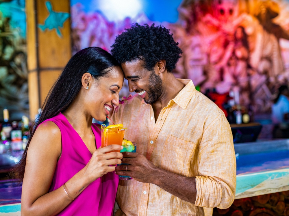 A couple cheers cocktails at a bar in The Bahamas. 