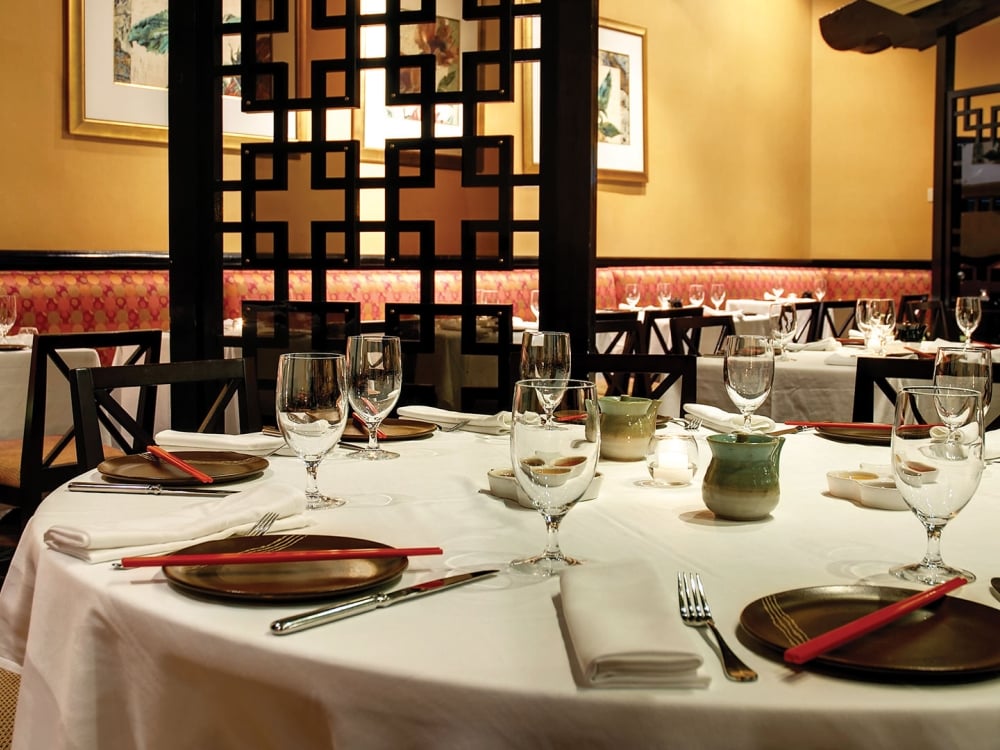 A table set with gold plates, glasses and chop sticks at an Asian-inspired restaurant.