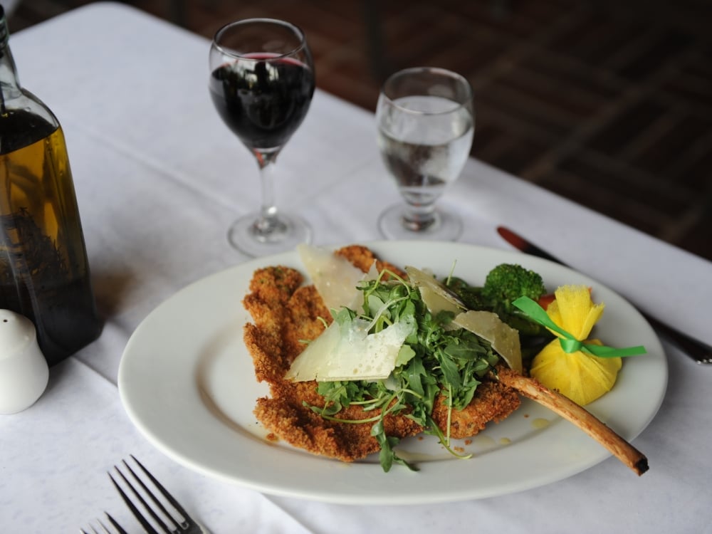 A plate of European-inspired food and glass of red wine. 