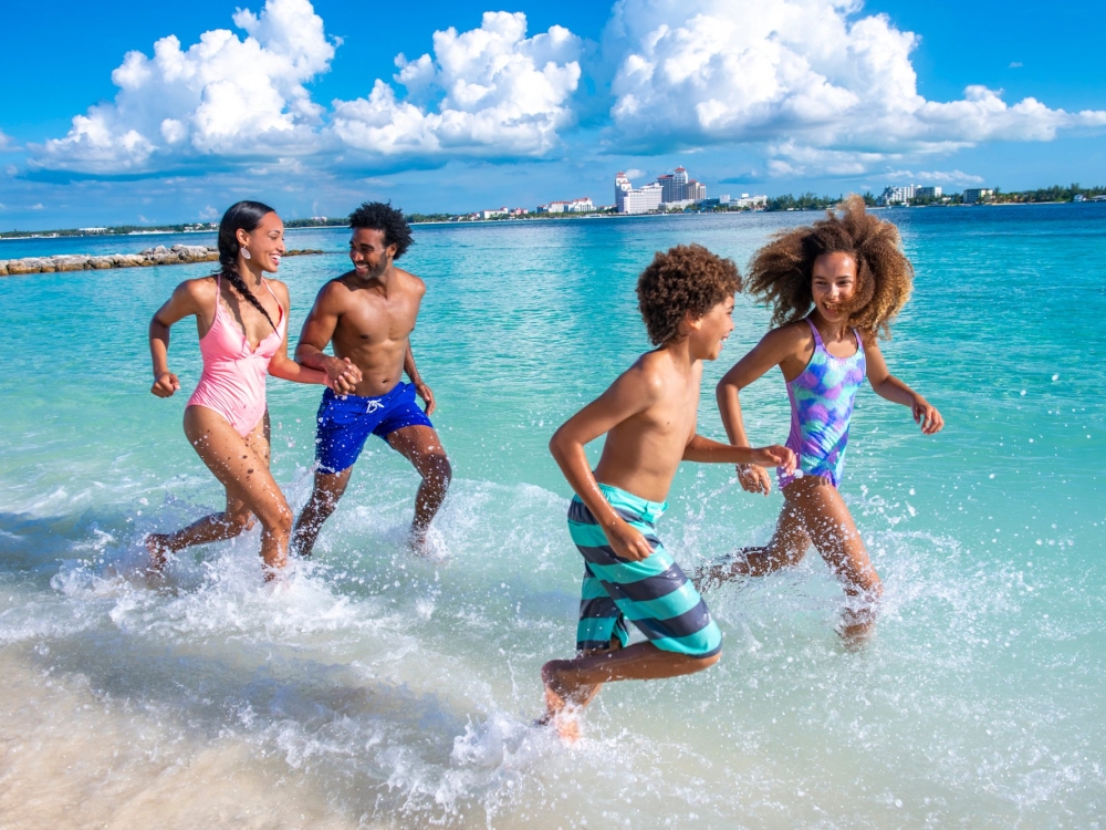 A family of fun splashes in the waves on a Bahamas beach.