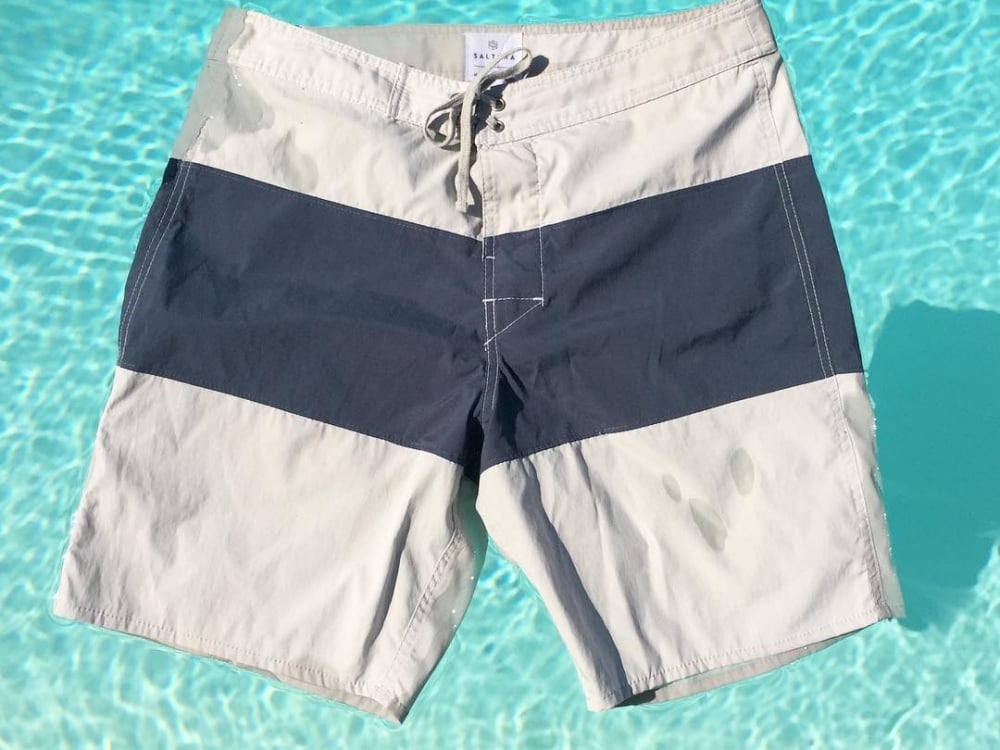 A pair of swim trunks float in a tropical pool.