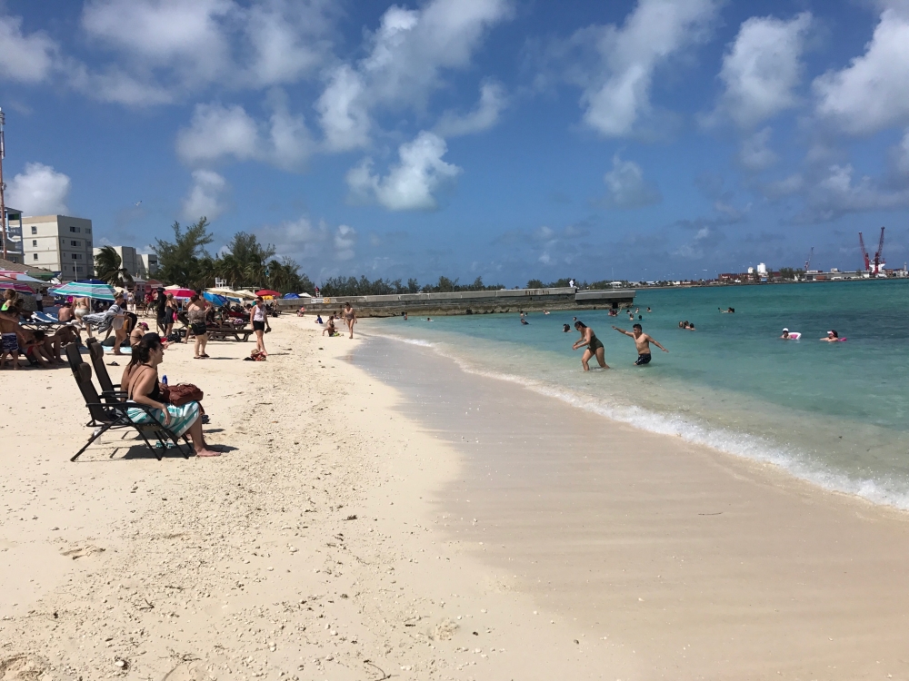 A crowd of beach lovers on a bustling Bahamas beach.