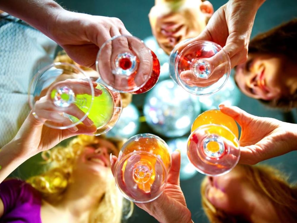 A group of people raise their glasses to cheers.