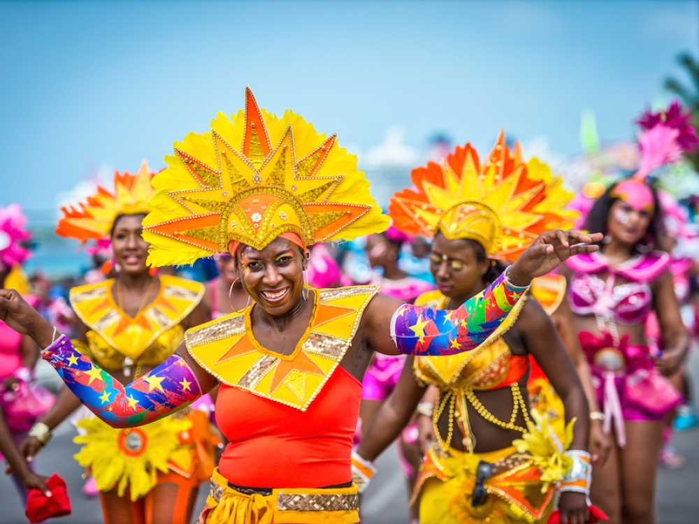 Women dressed in yellow and pink Junkanoo costumes parade on the street in Nassau.