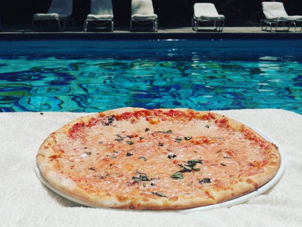 A pizza sitting on a white towel, poolside.