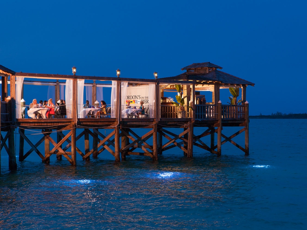 An evening photo of people dining at Gordon's on the Pier restaurant in The Bahamas.