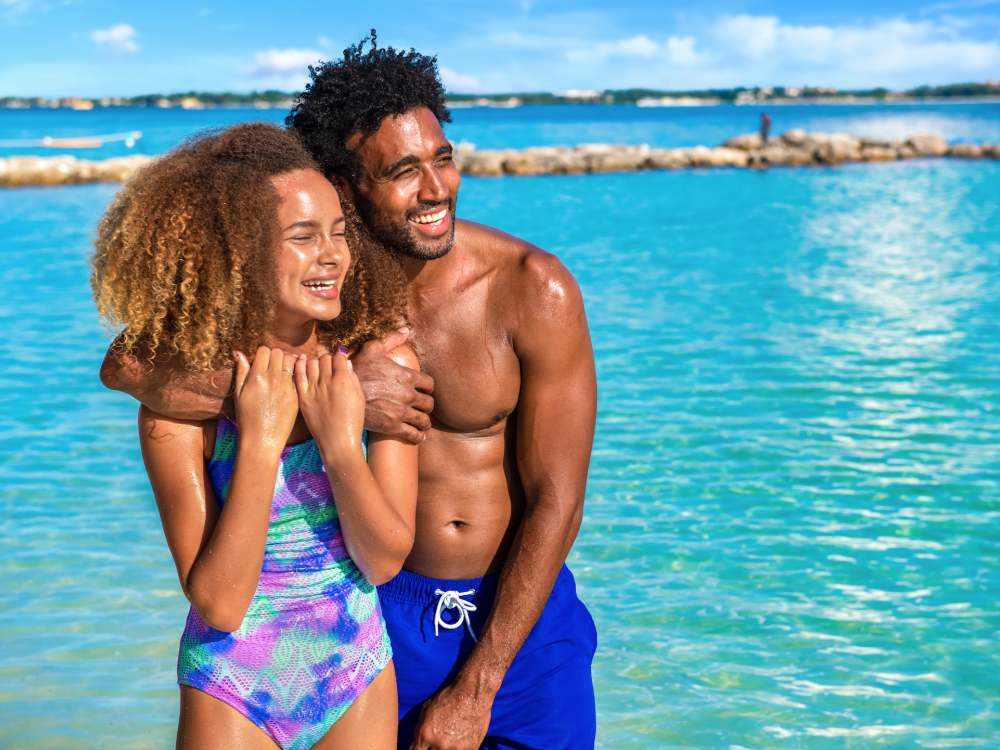 A dad and daughter pose for a photo next to the beach in The Bahamas.