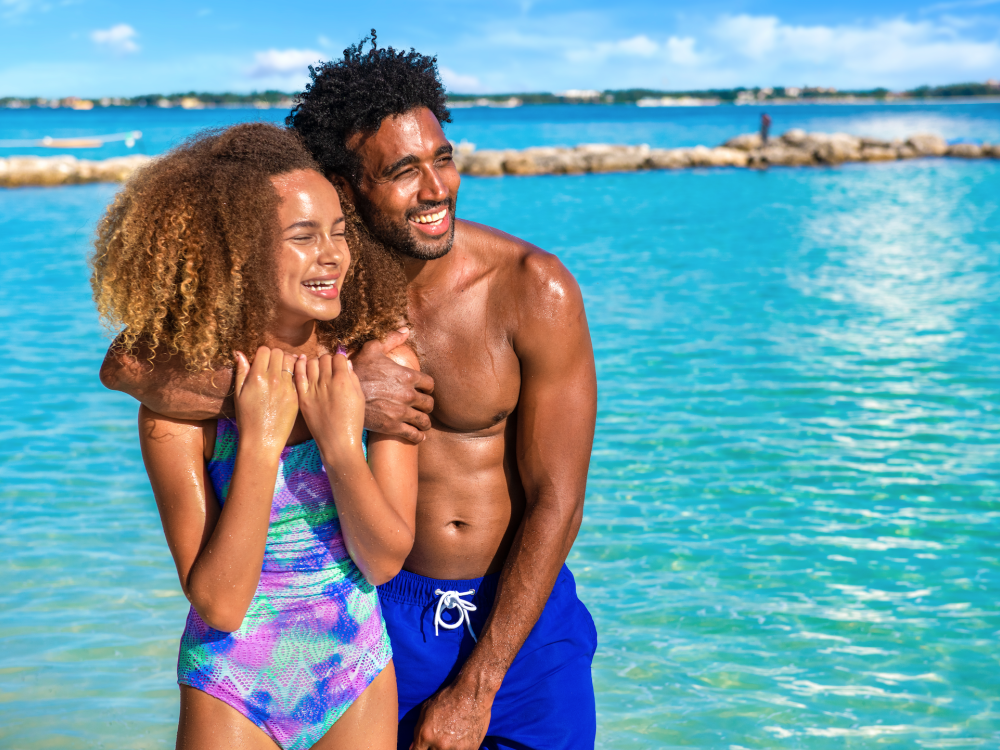 A dad and daughter pose for a photo next to the beach in The Bahamas. 