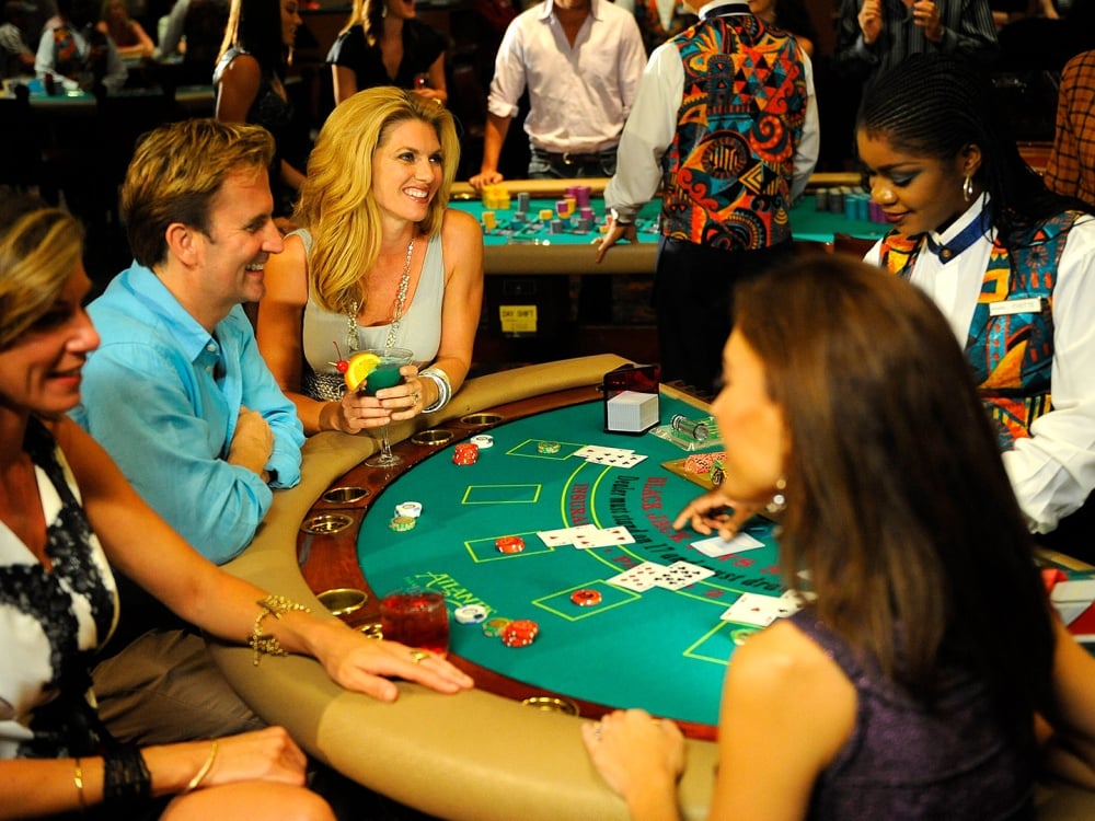 A group of people sitting around a table playing blackjack. 