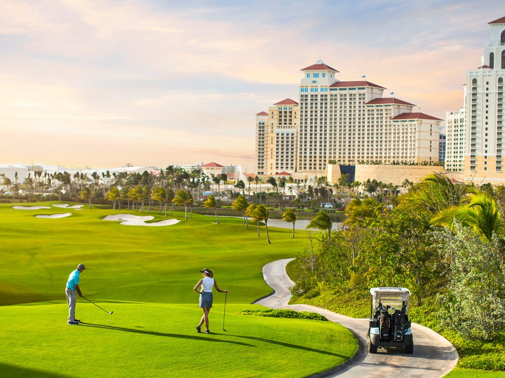 A man and a woman playing golf at Baha Mar Royal Blue Golf course.