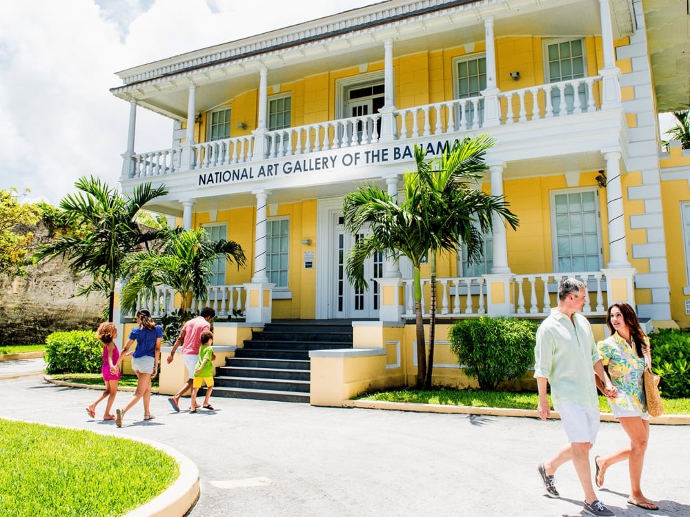 People walking in front of historical yellow house