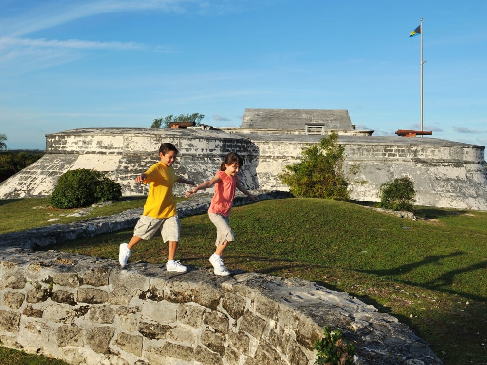 Two children run around a stone fortress.